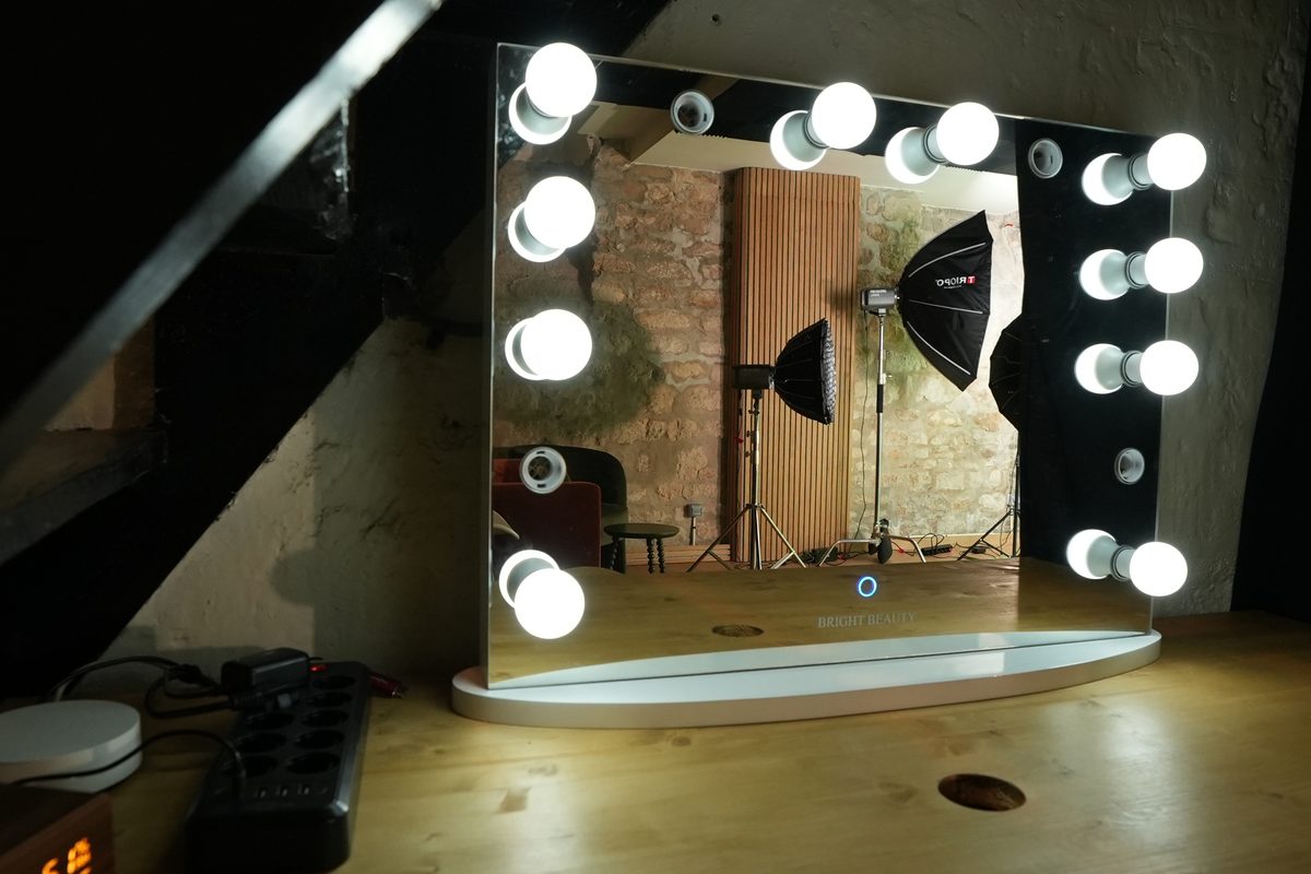 Miroir de maquillage lumineux posé sur la table en bois, sous l'escalier